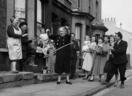 Old Kent Road, Mary Adams, aged 68, giving a hula hoop demonstration to admiring neighbours, c1958.  X..png